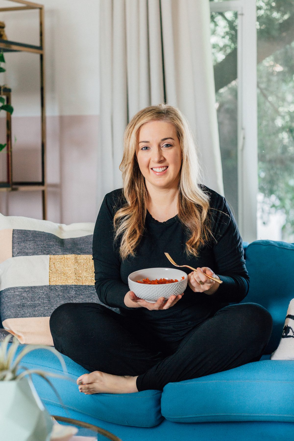 woman sitting on her couch and eating Healthy Comfort Food Hacks