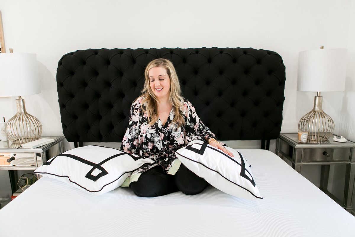 woman sitting on a bed with two pillows