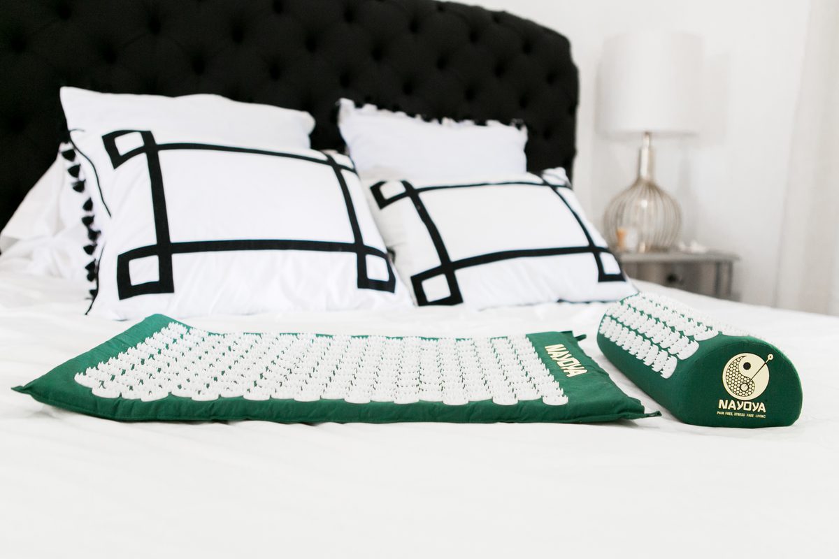 green Acupressure Mat and Neck Pillow set on a bed
