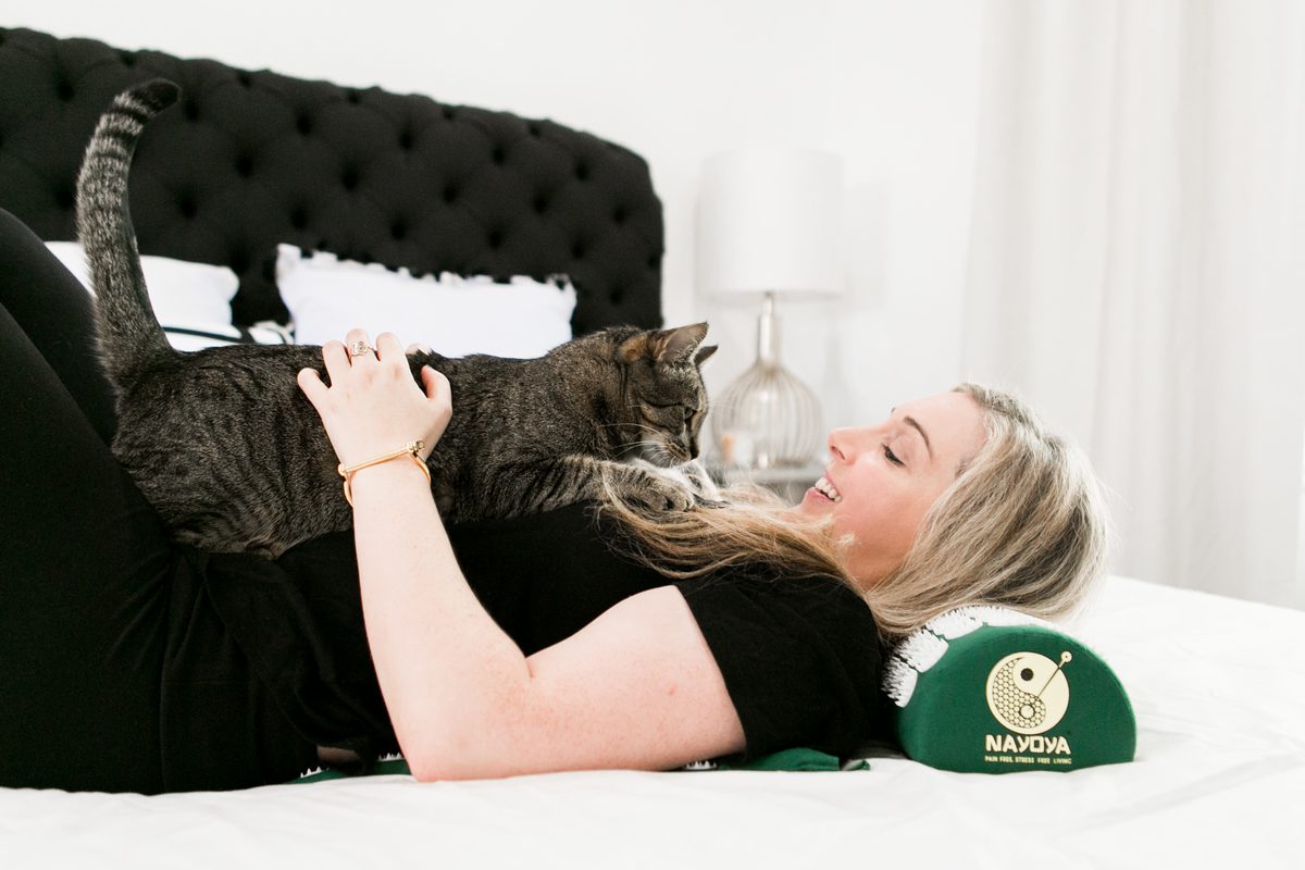 woman and her cat laying down on green Acupressure Mat and Neck Pillow 