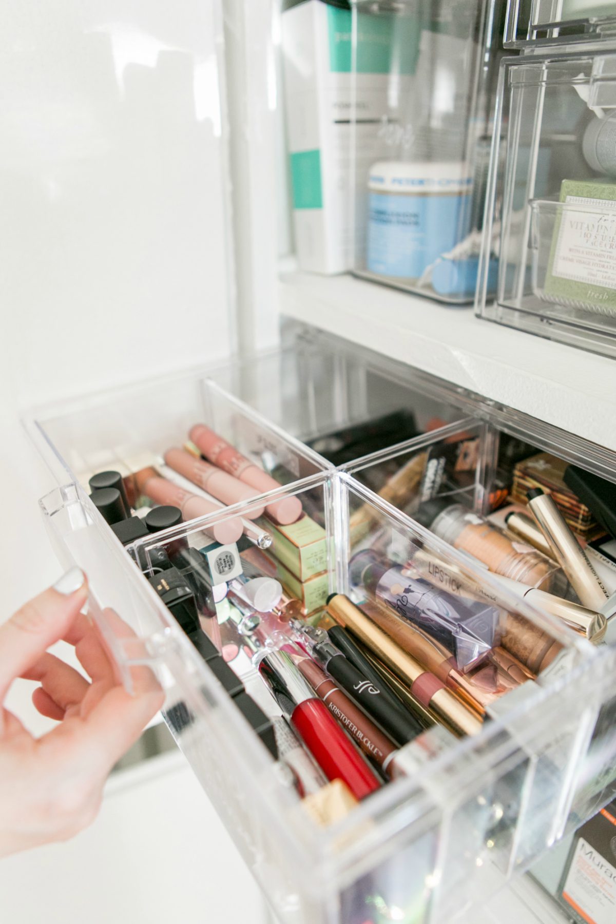 hand pulling a clear makeup container with makeup
