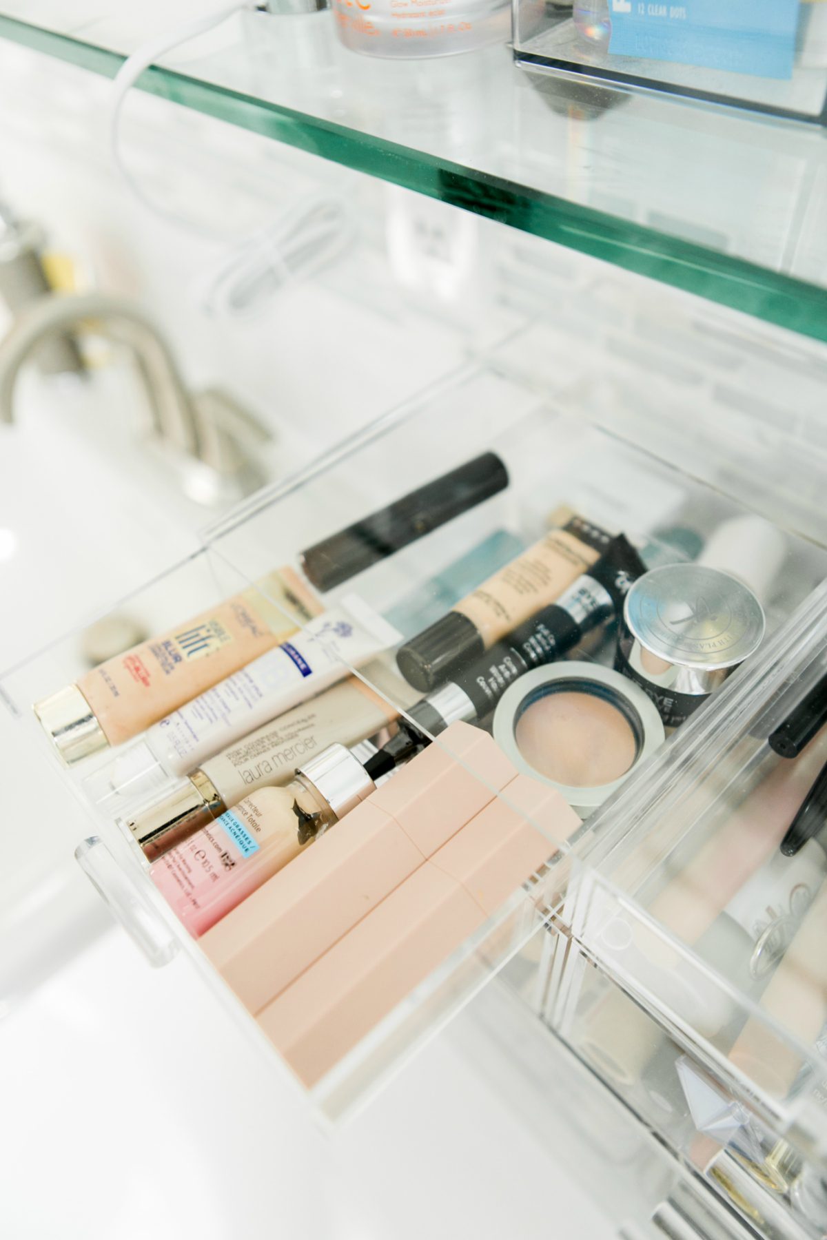 using clear containers to organize beauty products in a bathroom 