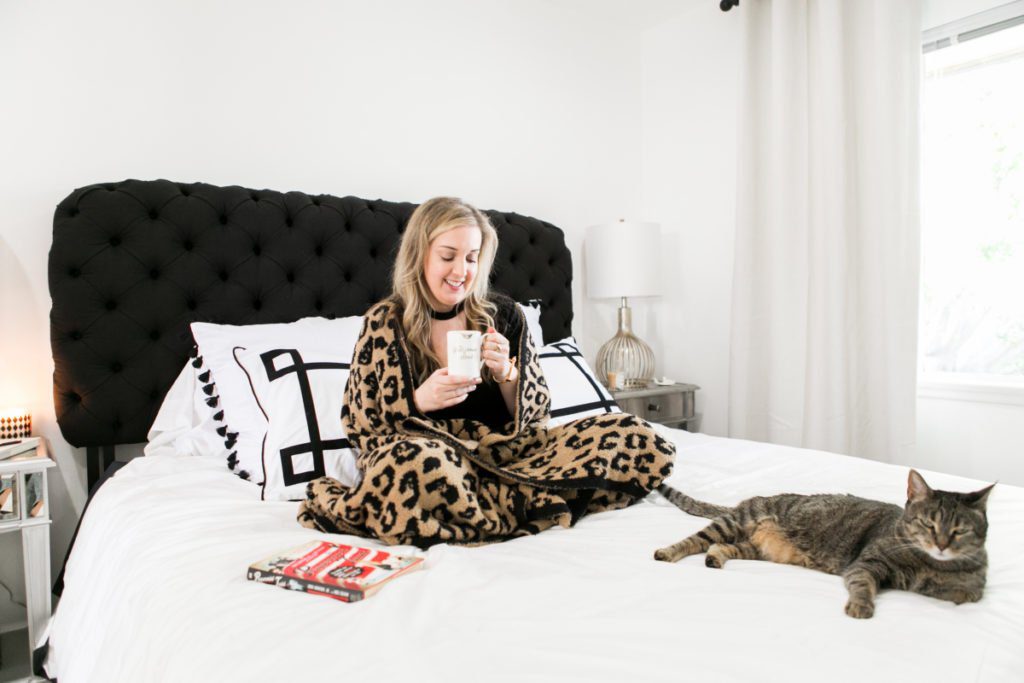 woman sitting on her bed with her cat